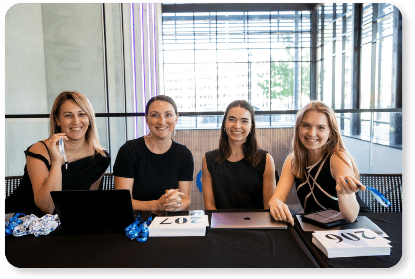 Four members of the BetterUnite team at an event check-in table with laptops and bid paddles